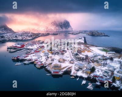 Vue aérienne de la montagne enneigée, village sur la côte de mer, ciel orange Banque D'Images