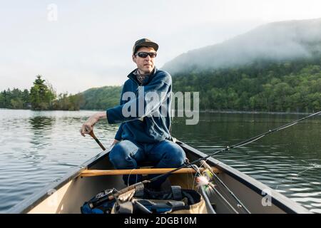 Canoë pêche à la mouche tôt le matin à Camden, Maine sur le lac Megunticook. Banque D'Images