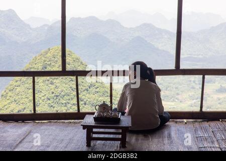 Une fille se trouve en face d'un paysage spectaculaire point de vue à Tan Lac, Vietnam, boire du thé. Banque D'Images