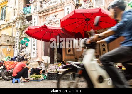 Vendeurs vietnamiens dans la ville chaotique de Hanoi, où les marchés de rue se trouvent parmi les motos et les véhicules Banque D'Images