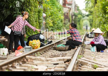 Les femmes qui travaillent Oh les voies de chemin de fer dans la rue de train de Hanoi, un site touristique populaire dans le vieux quartier Banque D'Images