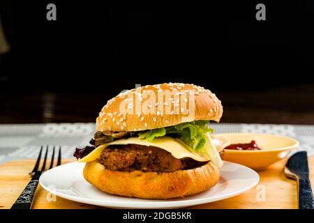 Hamburger de poulet maison avec fromage et légumes dans une assiette blanche Banque D'Images