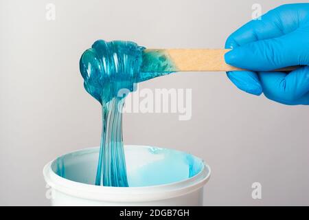 Pâte de sucre bleu liquide ou cire dépilatoire sur un bois tenez-vous au gros plan sur un fond blanc Banque D'Images
