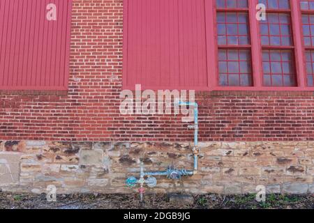 Bâtiment commercial en briques et murs de pierre mixtes extérieur, bois peint en rouge et fenêtres, tuyaux de gaz et mètre, aspect horizontal Banque D'Images