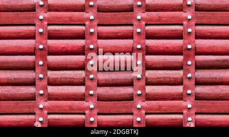 Motif en bois rouge, le mur est fait de rondins avec des bandes verticales en fer et des rivets Banque D'Images