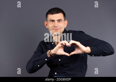 Le don, la charité et le concept de St.Valentin. Homme tenant un cœur hors de ses mains sur un fond noir. Banque D'Images