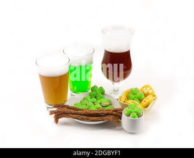 Bière vert camp clair et sombre dans un verre avec hors-d'œuvre sur une table avec des trèfles sur un backgro blanc Banque D'Images