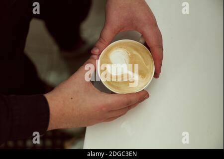 Beautyfut Latte Art. Tirage au sort. Un gros plan court sur les mains a conservé une tasse de latte Banque D'Images