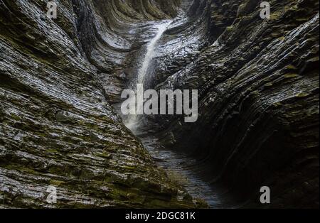 Cascade l'eau est éclairée par la lumière du soleil s'écoule vers le bas le mur lisse du canyon Banque D'Images