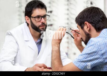 Ophtalmologiste offrant des lunettes pour un essai. Optométriste proposant de porter une paire de lunettes. Banque D'Images