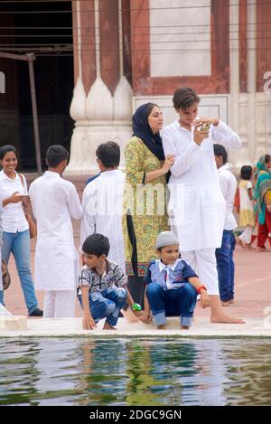 Des personnes se sont rassemblées près de la fontaine dans la cour centrale de la Jama Masjid, une mosquée de style moghol du XVIIe siècle, dans la vieille ville de Delhi, en Inde Banque D'Images