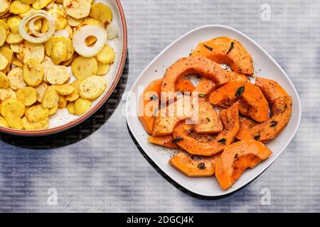 Pommes de terre grillées et courges au noyer cendré orange sur deux assiettes - vue de dessus vers le bas Banque D'Images