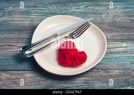 Assiette en céramique blanche avec coutellerie et coeur sur fond en bois. Banque D'Images