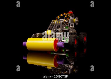 Rouleau routier de construction en métal pour enfant isolé pour l'éducation à l'assemblage mécanique sur fond noir Banque D'Images