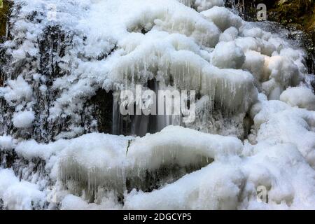 Belle chute d'eau gelée en hiver. De l'eau gelée et de la glace partout. Formations de glace étonnantes. Rayons lumineux qui brillent à travers les bois Banque D'Images