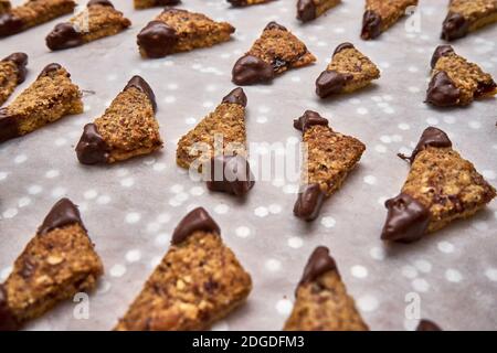 Biscuits aux noix de triangle remplis de confiture avec les extrémités trempées Dans le chocolat noir sur le papier de cuisson à l'étuvage Banque D'Images