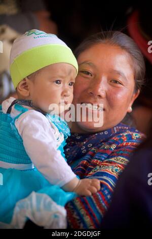 Monastère de Karsha, près de la vallée de Padum Zanskar, Ladakh, Jammu et Cachemire, nord IndiaLadakhi mère en robe de fête portant un jeune enfant. Festival Karsha Gustar, monastère de Karsha, près de la vallée de Padum Zanskar, Ladakh, Jammu-et-Cachemire, nord de l'Inde Banque D'Images