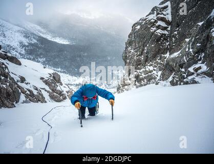 Le grimpeur alpin s'enorne sur une épaisse couche de neige une ascension de glace Banque D'Images