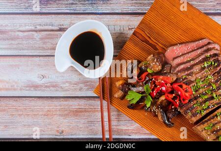 Bœuf rôti de bœuf coréen, piments rouges et champignons à bord avec baguettes. Banque D'Images