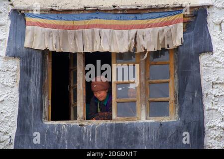 Ladakhi femme en tenue de fête locale à regarder des actes de festival depuis une fenêtre de monastère. Monastère de Karsha, près de Padum, vallée de Zanskar, Ladakh, Jammu-et-Cachemire, nord de l'Inde Banque D'Images