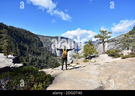Un randonneur mâle aux bras étendus au sommet des chutes du Nevada dans la vallée Little Yosemite, en face de Glacier point dans le parc national de Yosemite, en Californie Banque D'Images