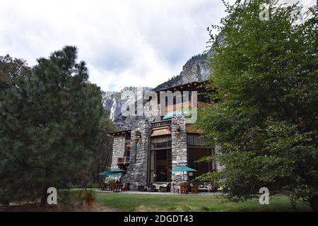 Une petite partie du luxueux Ahwahnee Hotel au milieu de la vallée de Yosemite entourée d'arbres et de grandes falaises de granit. Parc national de Yosemite. Banque D'Images