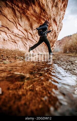 Femme randonneur saute sur le ruisseau tout en randonnée dans Canyon, Boulder Utah Banque D'Images