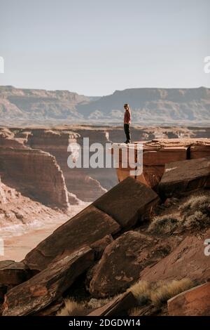 Une femme se trouve au bord d'une falaise surplombant le désert, Hite, Utah Banque D'Images