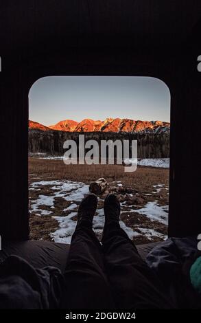 Vue de POV des jambes à l'extérieur de la porte de campeur avec vue sur la montagne coucher du soleil, Colorado Banque D'Images