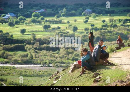 La longue route de Padum, Zanskar, à Kargil, devient cultivée et luxuriante à l'approche de Kargil. Des villageois musulmans attendent leur transport sur la route. District de Kargil, Ladakh, Jammu-et-Cachemire, Inde Banque D'Images