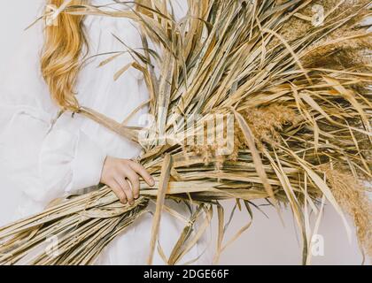 Fille en robe vintage blanche est tenue grand bouquet de champs plantes dans ses mains Banque D'Images