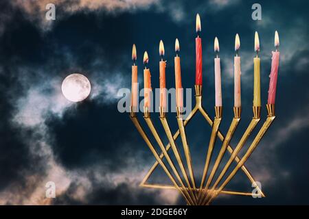 Hanukkah menorah avec des étincelles sur pleine lune dans les nuages arrière-plan Banque D'Images