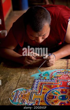 Monk au monastère de Lamayuru, Ladakh créant un mandala de sable coloré. Lamayouro, Ladakh, Jammu-et-Cachemire, Inde. Un mandala de sable est ritualistiquement démantelé une fois qu'il a été achevé et ses cérémonies d'accompagnement et de visualisation sont terminées pour symboliser la croyance doctrinale bouddhiste dans la nature transitoire de la vie matérielle. Banque D'Images