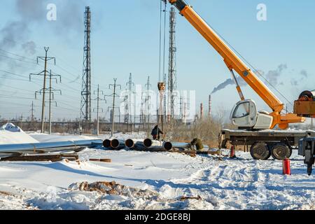 Travaux de construction sur la pose de canalisations dans la tranchée à l'aide d'une grue Banque D'Images