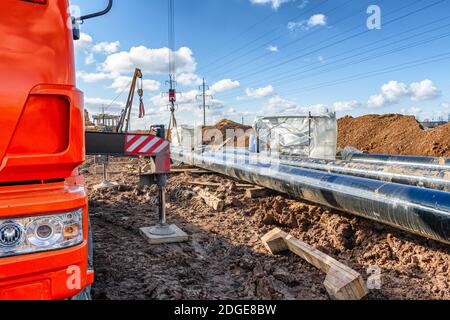 Travaux de construction sur la pose de canalisations dans la tranchée à l'aide d'une grue Banque D'Images