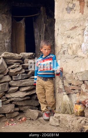 Portrait d'un garçon Zanskari avec un balai à l'extérieur de sa maison, vallée de Zanskar, Ladakh, Jammu & Cachemire, Inde Banque D'Images