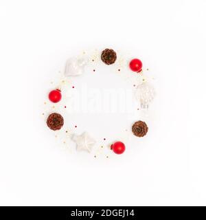 Cadre rond de Noël fait de décorations rouges, de cônes de pin, de confettis et de paillettes sur fond blanc. Couronne isolée du nouvel an. Lay Lay Lay, espace de copie Banque D'Images