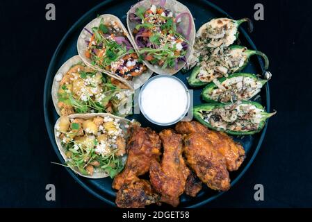 Vue en hauteur d'une délicieuse assiette de dégustation de hors-d'œuvre avec des tacos au poulet et au steak, des papers et des ailes de buffles fait que l'eau de la bouche et l'estomac se développent Banque D'Images