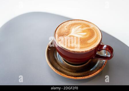Café du matin dans une tasse en céramique avec mousse sur une soucoupe. Pause café dans un café. Cappuccino frais aromatique. Tasse à café sur la table. Vue de dessus. Banque D'Images