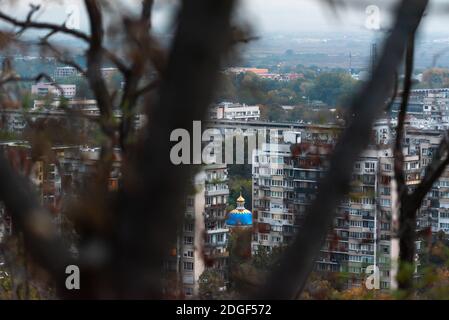 Coucher de soleil lumineux sur une ville à travers la nature branches arbres sur la colline à Plovdiv, Bulgarie Banque D'Images