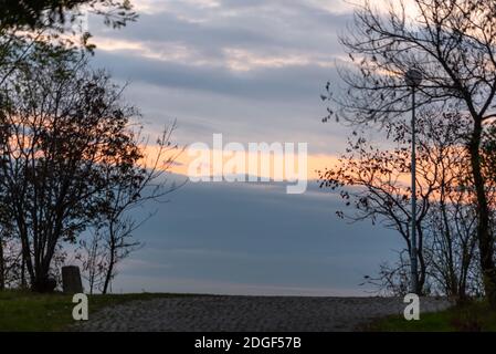 Coucher de soleil lumineux sur une ville à travers la nature branches arbres sur la colline à Plovdiv, Bulgarie Banque D'Images