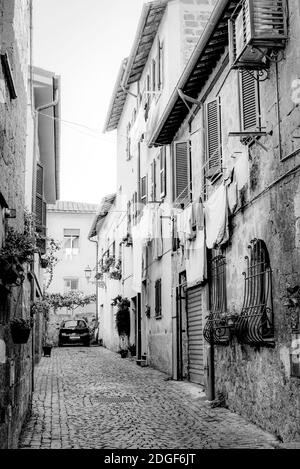 Une rue médiévale étroite avec des maisons avec des étages ajoutés à Orvieto, Ombrie, Italie. Photo en noir et blanc Banque D'Images