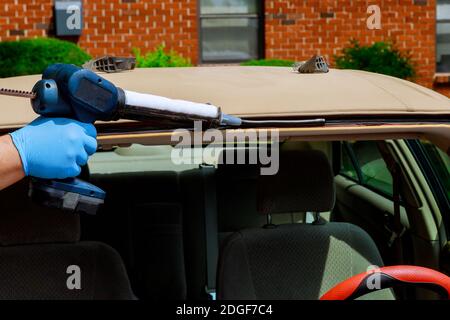 Vitrier à l'aide d'outils en silicone pour réparer le pare-brise sur une voiture automobile remplacement du pare-brise Banque D'Images