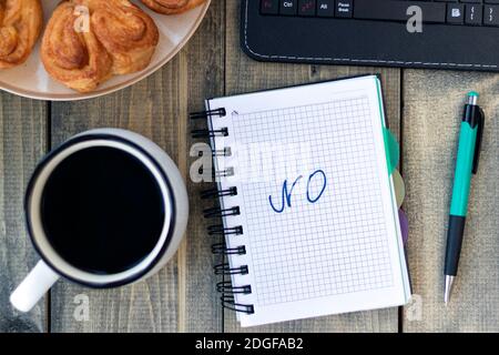 Le mot NO dans le carnet de la table de travail avec une tasse de café et un petit pain. Concept de recrutement d'emplois. Pose à plat Banque D'Images