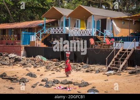 PALOLEM, Goa, INDE - 19 MARS 2019 : une indienne en robe traditionnelle saree porte un seau sur sa tête le long des maisons du village sur la rive du TH Banque D'Images