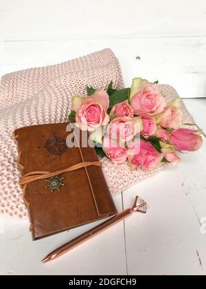 Roses roses et carnet en cuir sur une couverture rose Banque D'Images