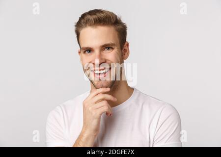 Très bien. Intrigué et heureux jeune homme réfléchi, souriant hochant satisfait en accord, touchant le menton, d'accord avec un ami, fou Banque D'Images