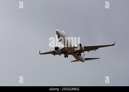 Avion de ligne entrant dans la terre sous de lourds nuages de pluie. (Anonymisé, marque distinctive retirée). Banque D'Images