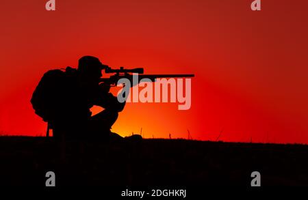 Sniper de l'équipe de commando, tir de tir des forces spéciales de l'armée, tir de fusil de sniper tout en étant assis sur la mer ou sur la côte de l'océan pendant le coucher du soleil. Un soldat de la côte ou du garde-frontière observe la côte avec une vue optique Banque D'Images