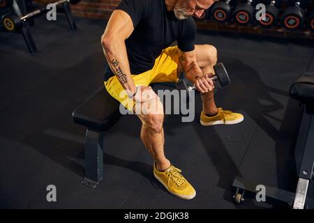 Un athlète concentré qui fait la boucle de la dumbbell assise Banque D'Images